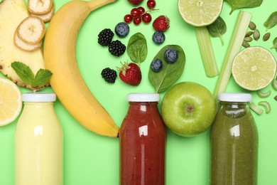 Photo of Superfood. Tasty smoothies in glass bottles and ingredients on green background, flat lay