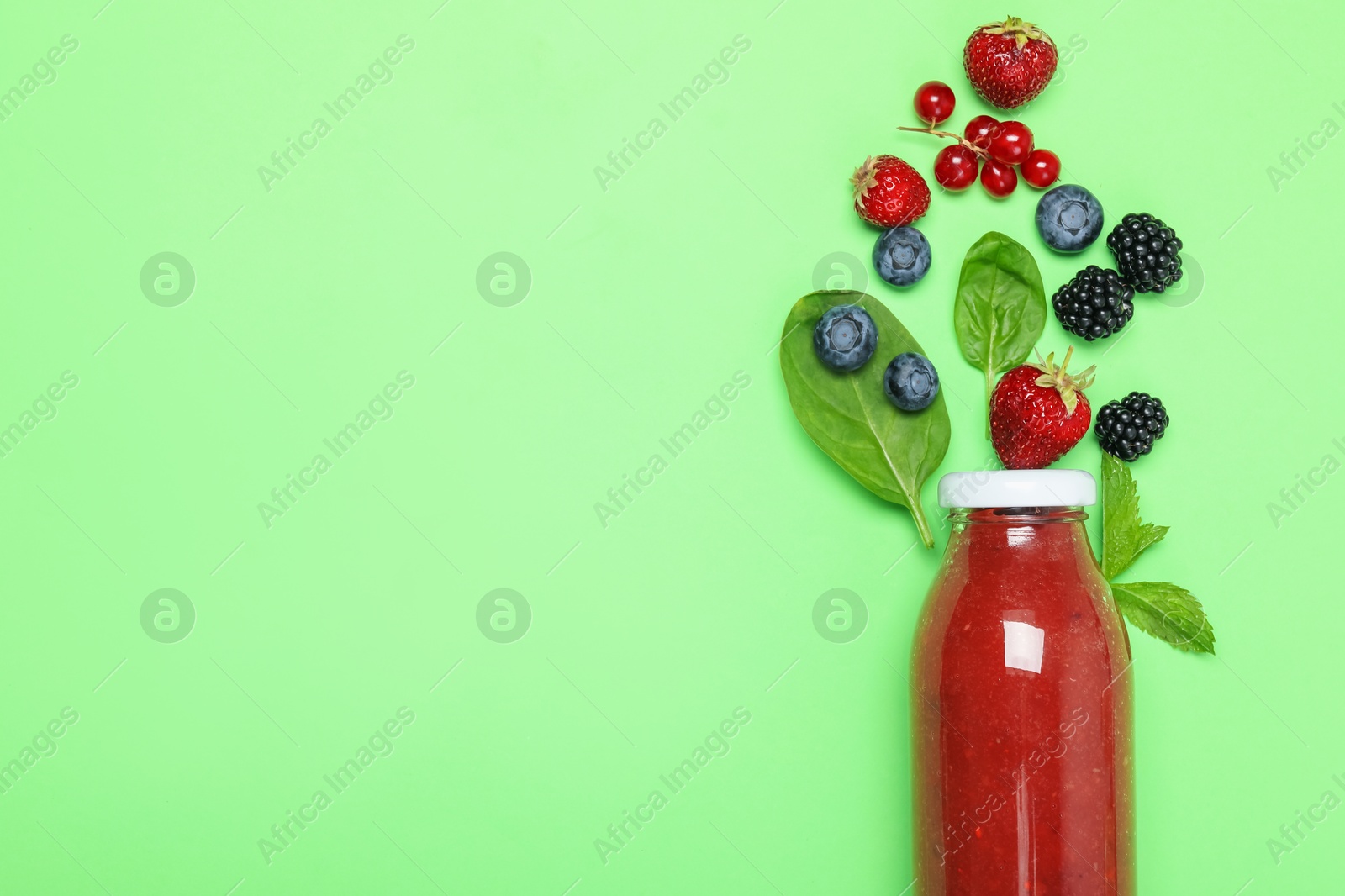 Photo of Superfood. Tasty smoothie in glass bottle and ingredients on green background, flat lay. Space for text