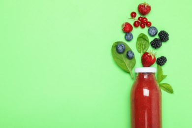Photo of Superfood. Tasty smoothie in glass bottle and ingredients on green background, flat lay. Space for text