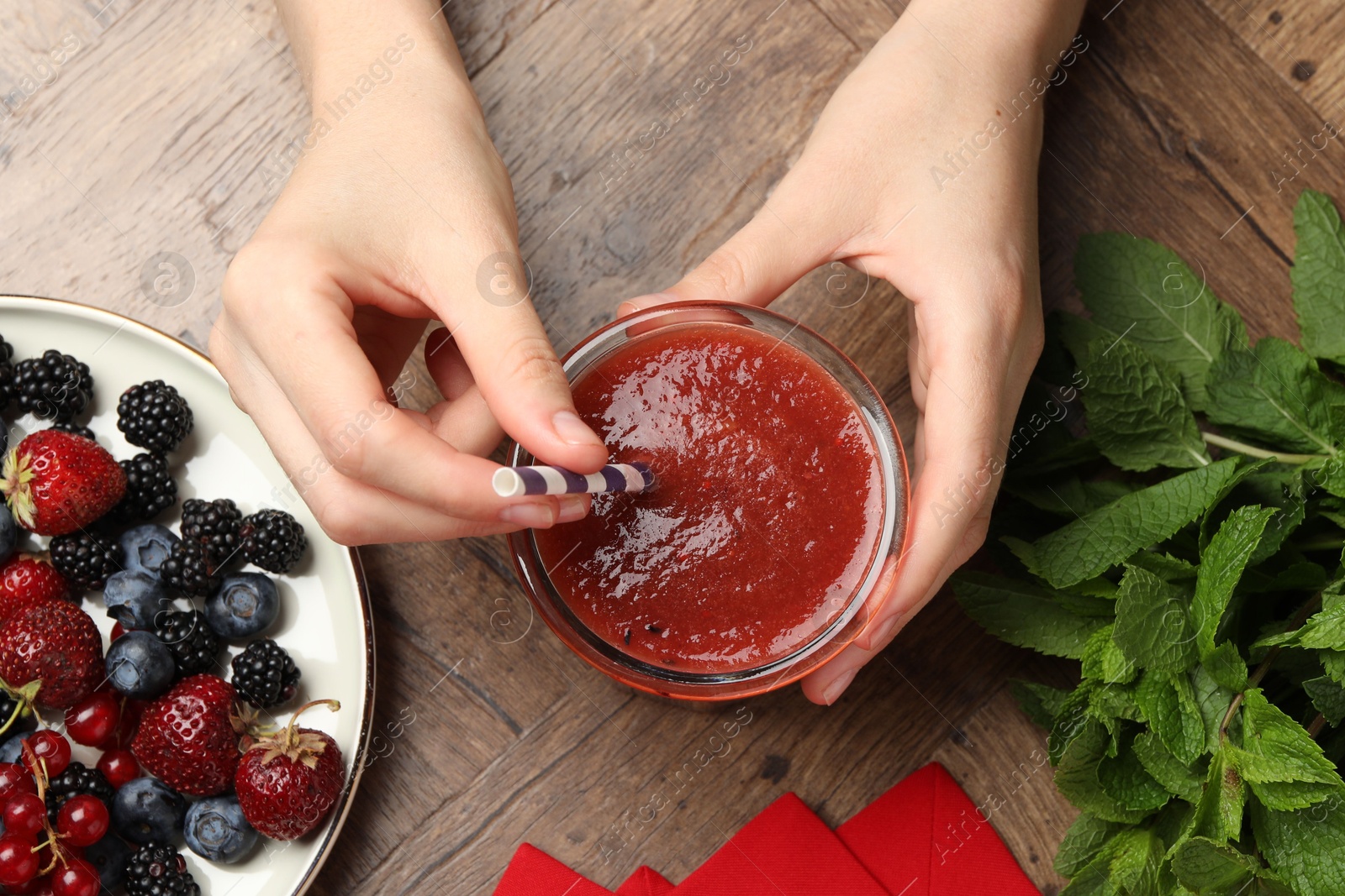 Superfood. Woman with tasty smoothie and ingredients at wooden table, top view Photo of Superfood. Woman with tasty smoothie and ingredients at wooden table, top view