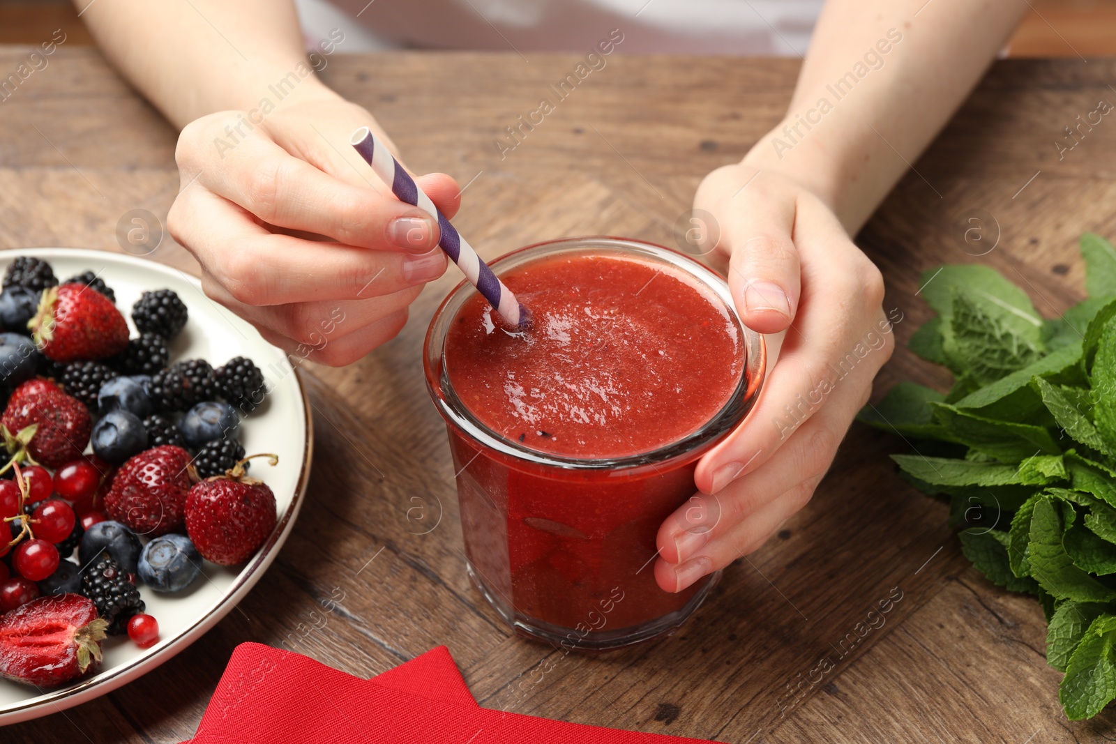 Superfood. Woman with tasty smoothie and ingredients at wooden table, closeup Photo of Superfood. Woman with tasty smoothie and ingredients at wooden table, closeup