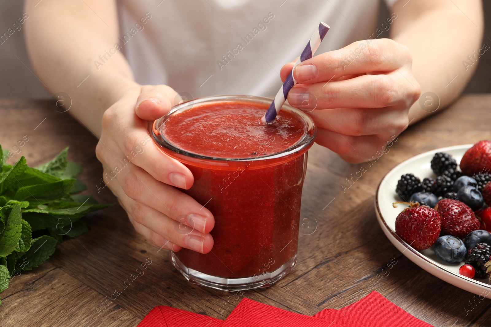 Superfood. Woman with tasty smoothie and ingredients at wooden table, closeup Photo of Superfood. Woman with tasty smoothie and ingredients at wooden table, closeup