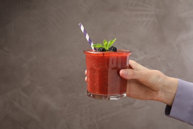 Photo of Superfood. Woman with tasty smoothie on grey background, closeup. Space for text