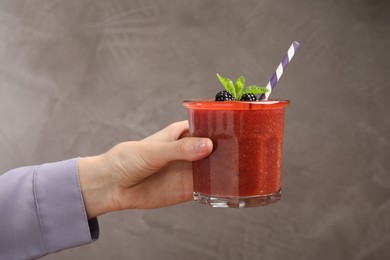 Photo of Superfood. Woman with tasty smoothie on grey background, closeup