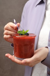 Photo of Superfood. Woman with tasty smoothie on grey background, closeup
