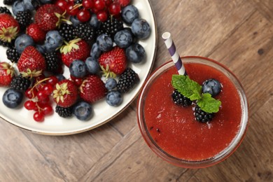 Photo of Superfood. Tasty smoothie in glass and ingredients on wooden table, flat lay