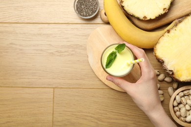 Photo of Superfood. Woman with tasty smoothie and ingredients at wooden table, top view. Space for text