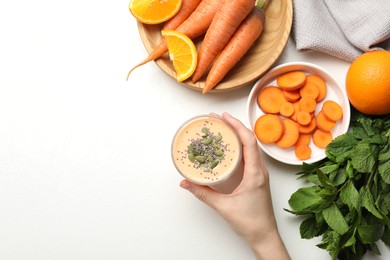 Photo of Superfood. Woman with tasty smoothie and ingredients at white table, top view. Space for text