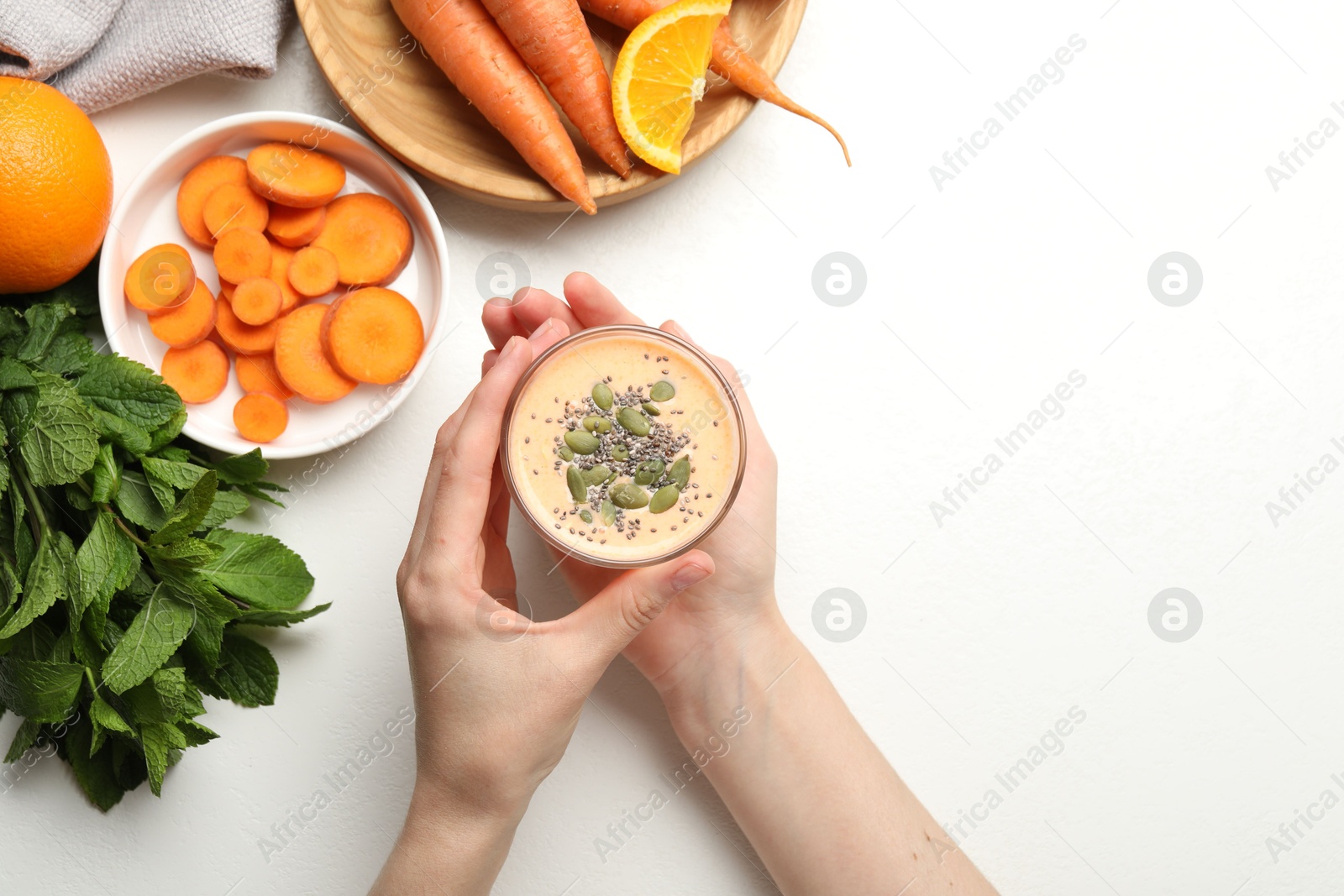 Superfood. Woman with tasty smoothie and ingredients at white table, top view Photo of Superfood. Woman with tasty smoothie and ingredients at white table, top view