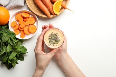 Photo of Superfood. Woman with tasty smoothie and ingredients at white table, top view
