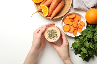 Photo of Superfood. Woman with tasty smoothie and ingredients at white table, top view