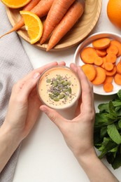 Photo of Superfood. Woman with tasty smoothie and ingredients at white table, top view