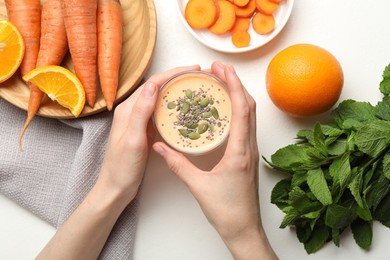 Photo of Superfood. Woman with tasty smoothie and ingredients at white table, top view