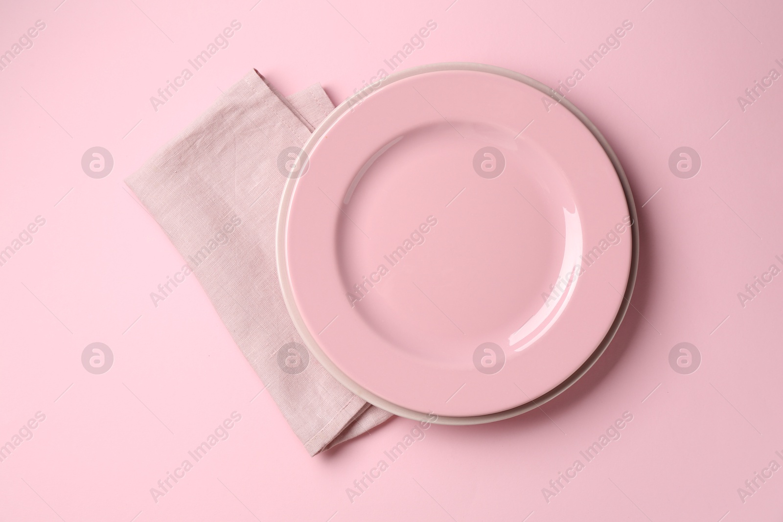 Stylish plates and napkin on pink background, top view Photo of Stylish plates and napkin on pink background, top view