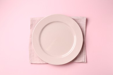 Photo of Stylish plate and napkin on pink background, top view