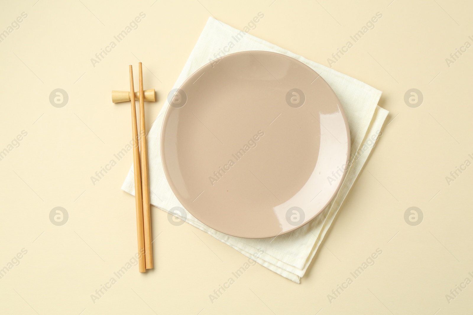 Stylish plate, chopsticks and napkin on beige background, flat lay Photo of Stylish plate, chopsticks and napkin on beige background, flat lay
