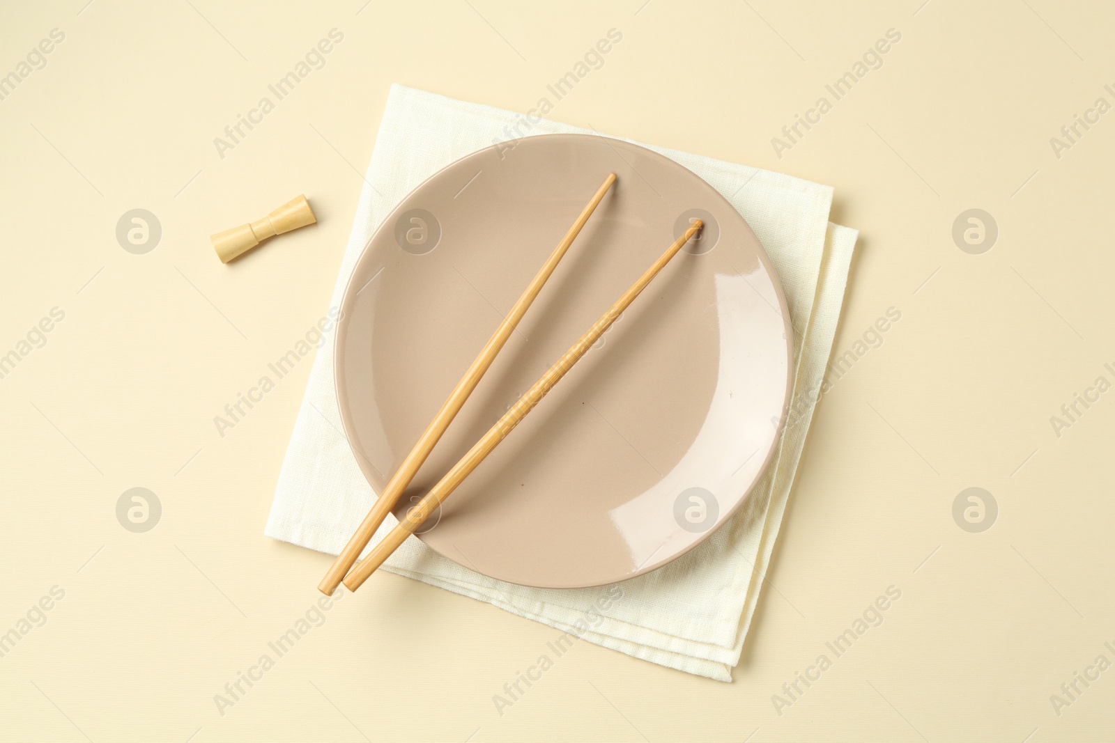 Stylish plate, chopsticks and napkin on beige background, flat lay Photo of Stylish plate, chopsticks and napkin on beige background, flat lay