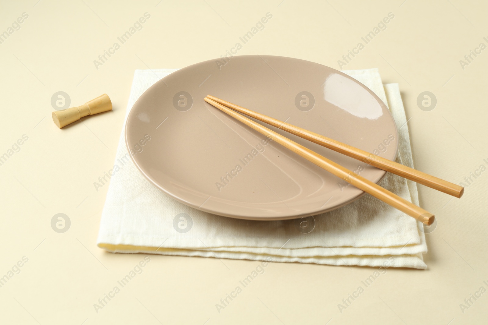 Stylish plate, chopsticks and napkin on beige background, closeup Photo of Stylish plate, chopsticks and napkin on beige background, closeup