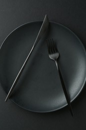 Photo of Stylish plate and cutlery on black background, top view