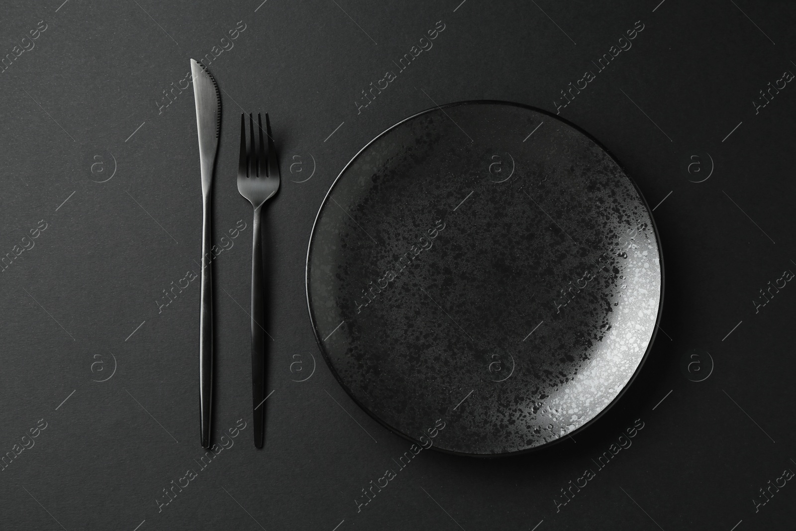Stylish plate and cutlery on black background, flat lay Photo of Stylish plate and cutlery on black background, flat lay