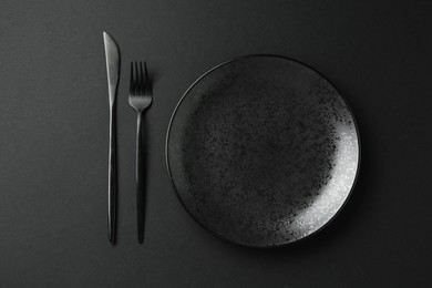 Photo of Stylish plate and cutlery on black background, flat lay