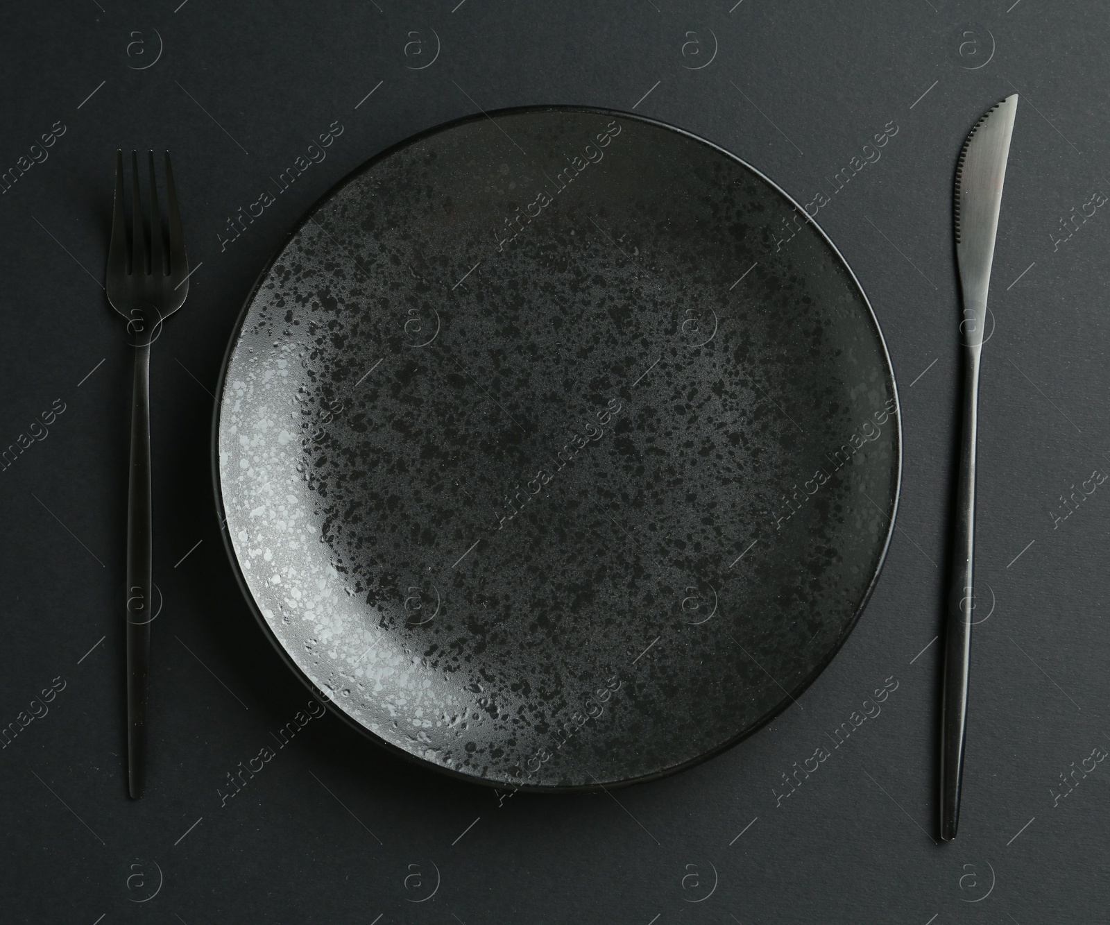 Stylish plate and cutlery on black background, flat lay Photo of Stylish plate and cutlery on black background, flat lay