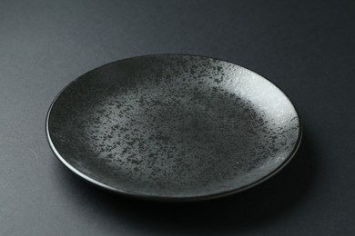 Photo of One stylish plate on black background, closeup
