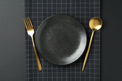 Photo of Stylish plate, cutlery and runner on black background, flat lay