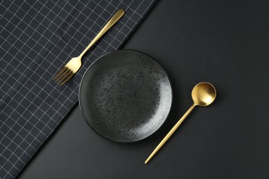 Photo of Stylish plate, cutlery and runner on black background, flat lay
