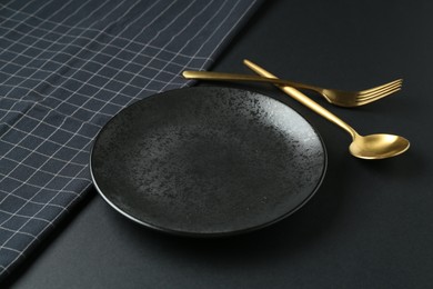 Photo of Stylish plate, cutlery and runner on black background, closeup