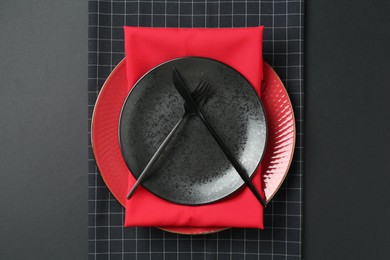 Photo of Stylish plates, cutlery and napkins on black background, top view