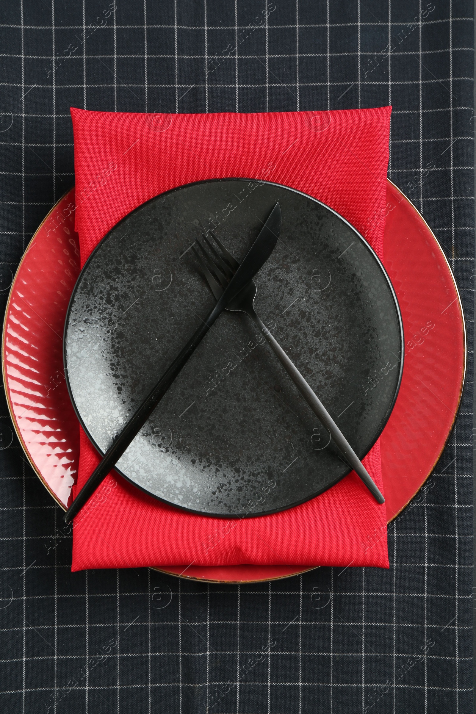 Stylish plates, cutlery and napkins on black background, top view Photo of Stylish plates, cutlery and napkins on black background, top view