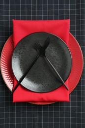 Photo of Stylish plates, cutlery and napkins on black background, top view