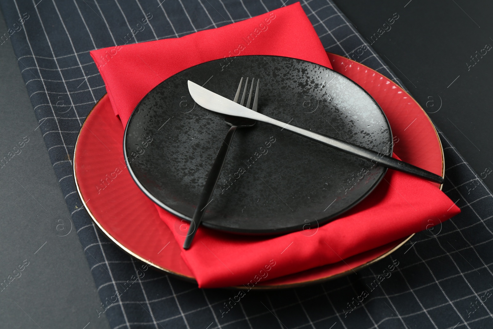Stylish plates, cutlery and napkins on black background, closeup Photo of Stylish plates, cutlery and napkins on black background, closeup