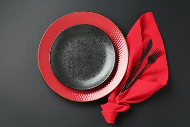 Photo of Stylish plates, cutlery and napkin on black background, flat lay
