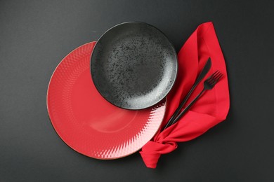 Photo of Stylish plates, cutlery and napkin on black background, flat lay