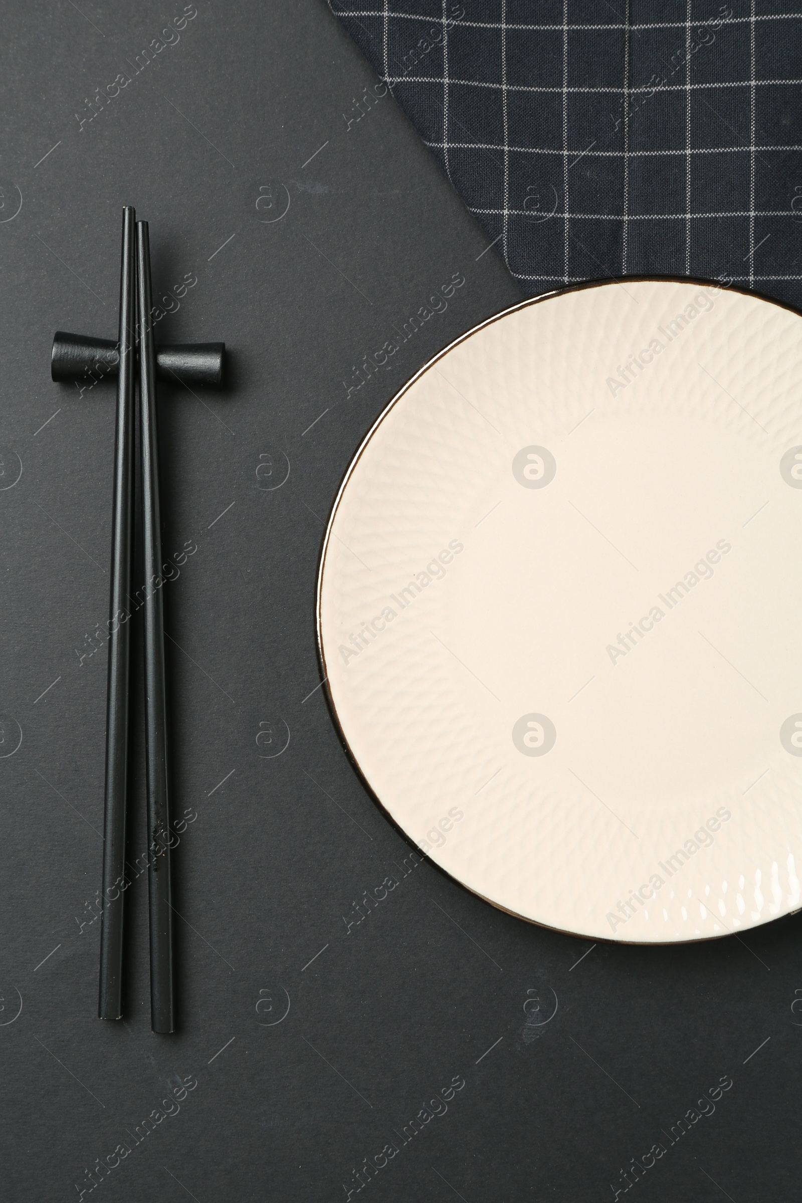 Stylish plate, chopsticks and napkin on black background, flat lay Photo of Stylish plate, chopsticks and napkin on black background, flat lay
