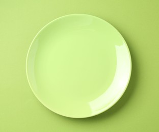 Photo of One stylish plate on green background, top view