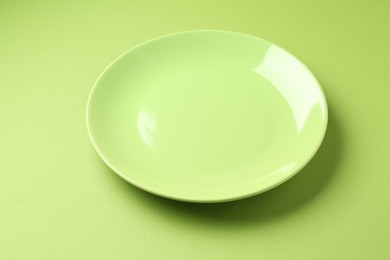 Photo of One stylish plate on green background, closeup