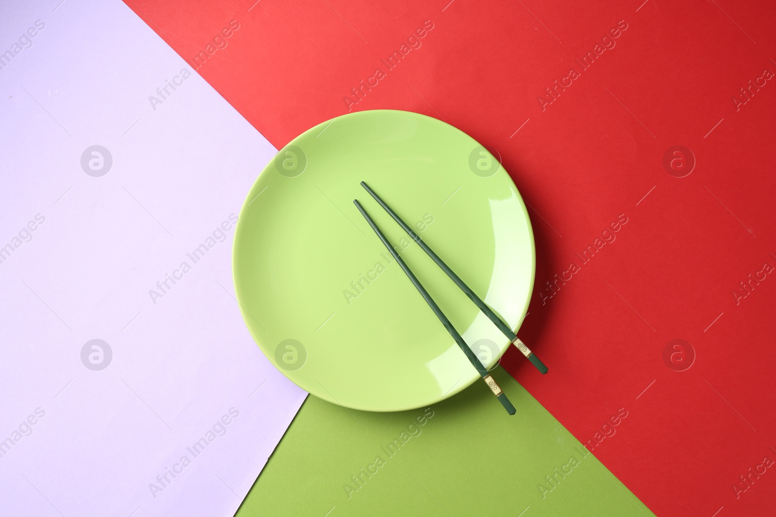Stylish plate and chopsticks on color background, top view Photo of Stylish plate and chopsticks on color background, top view