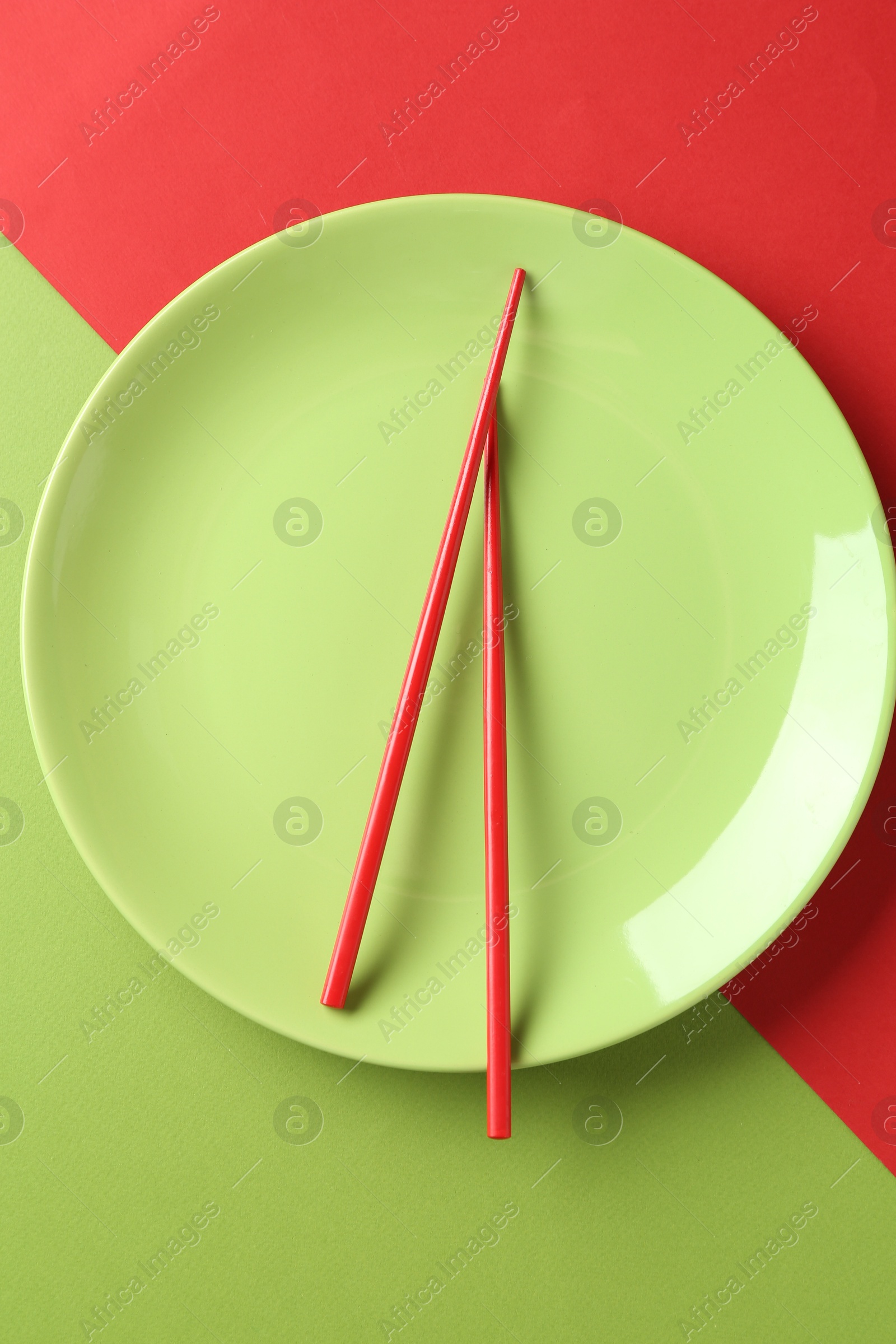 Stylish plate and chopsticks on color background, top view Photo of Stylish plate and chopsticks on color background, top view