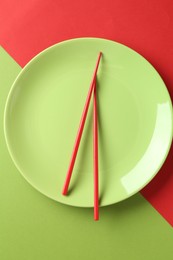 Photo of Stylish plate and chopsticks on color background, top view