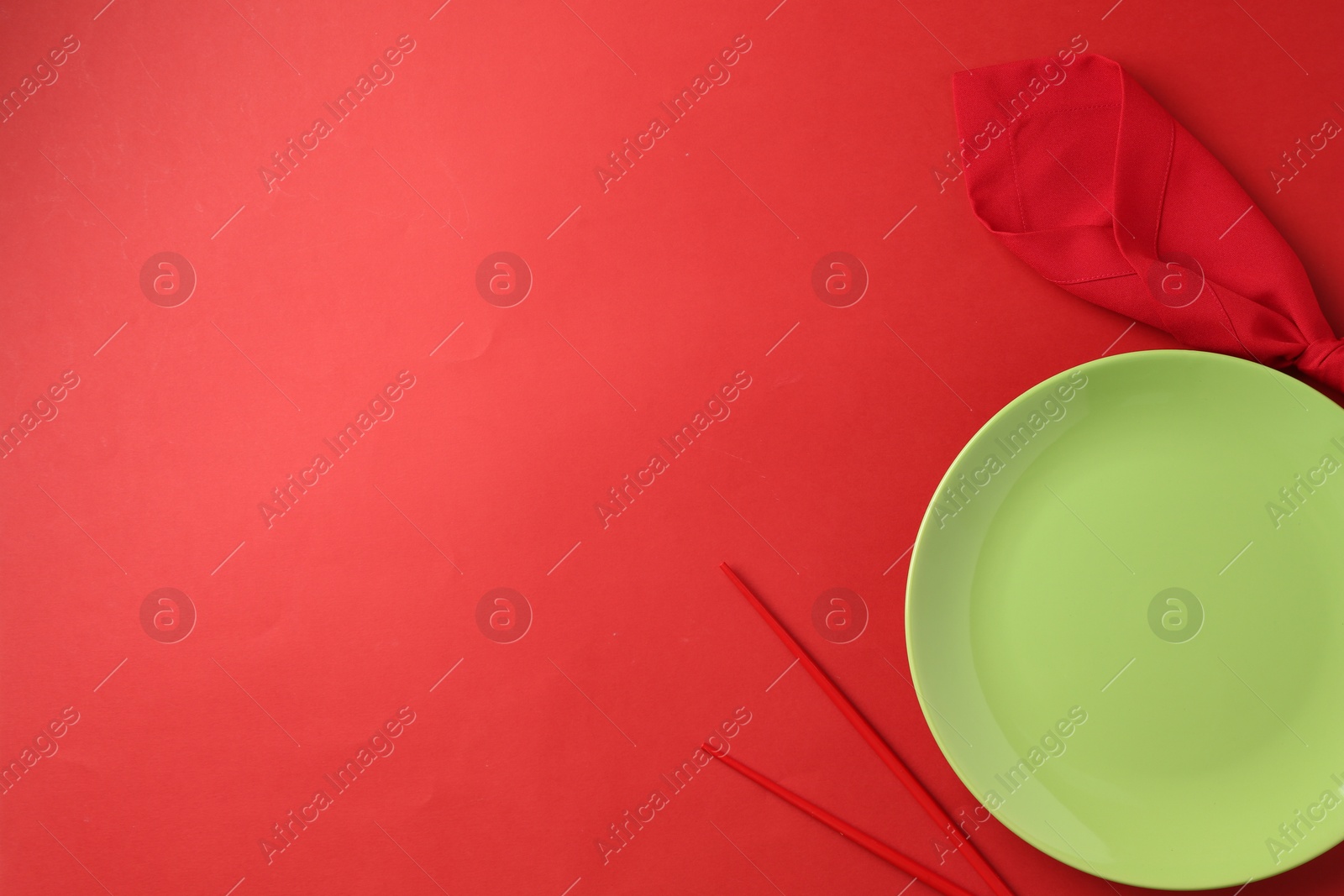 Stylish plate, chopsticks and napkin on red background, flat lay. Space for text Photo of Stylish plate, chopsticks and napkin on red background, flat lay. Space for text