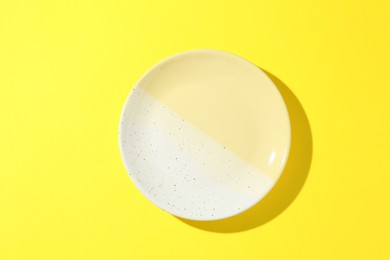 Photo of One stylish plate on yellow background, top view