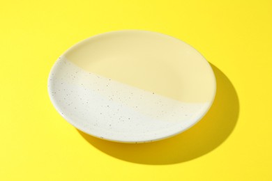 Photo of One stylish plate on yellow background, closeup