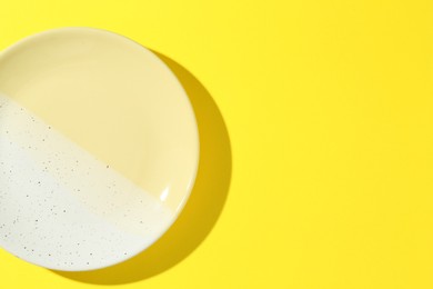 Photo of One stylish plate on yellow background, top view. Space for text