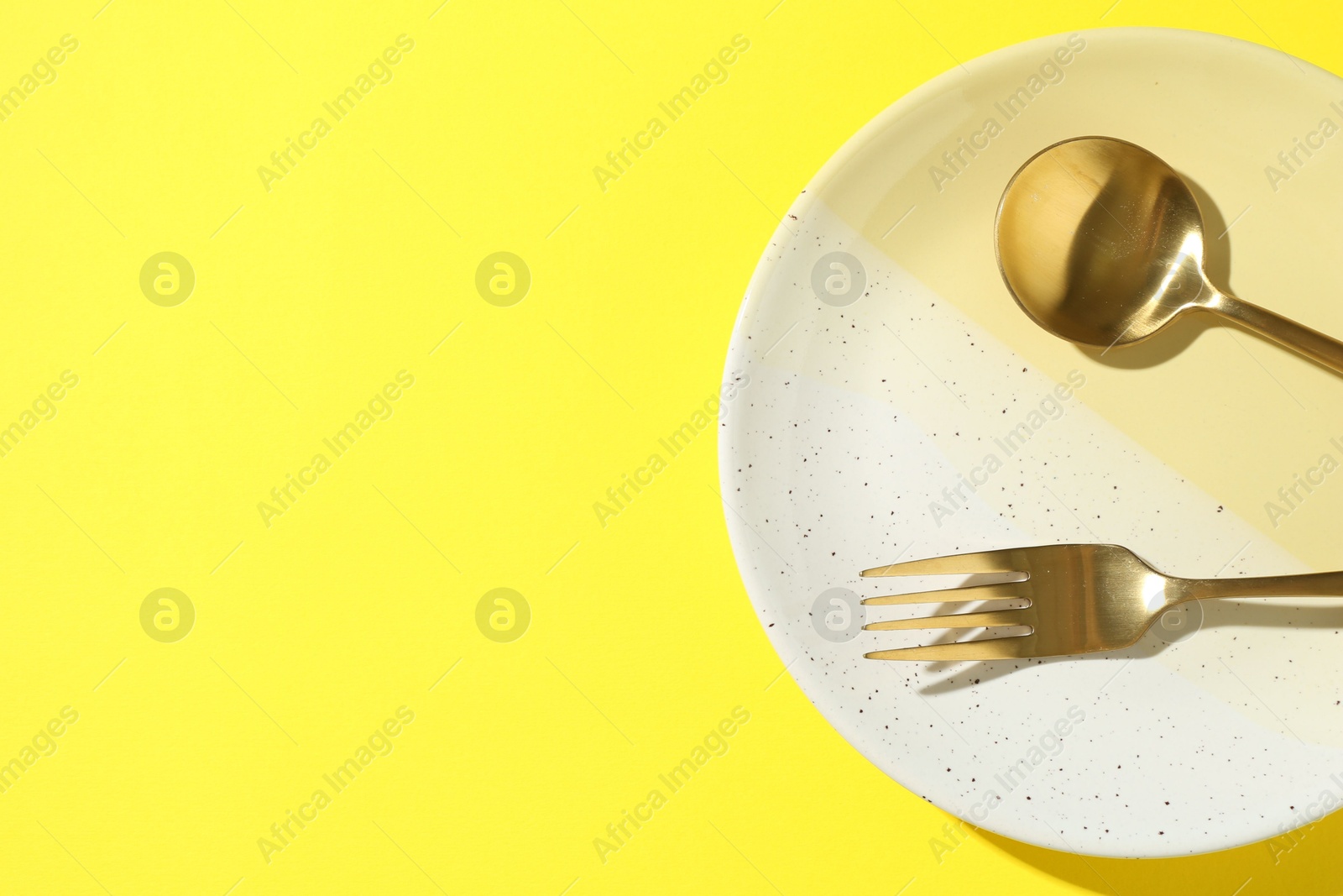 Stylish plate and cutlery on yellow background, top view. Space for text Photo of Stylish plate and cutlery on yellow background, top view. Space for text