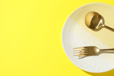 Photo of Stylish plate and cutlery on yellow background, top view. Space for text
