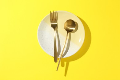 Photo of Stylish plate and cutlery on yellow background, top view