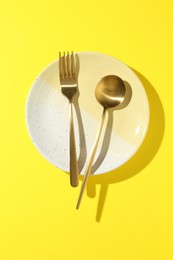 Photo of Stylish plate and cutlery on yellow background, top view
